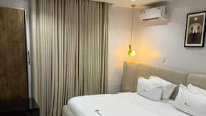 Een moderne hotelkamer met een groot bed, een nachtkastje, een kledingkast en een airconditioning op de muur.