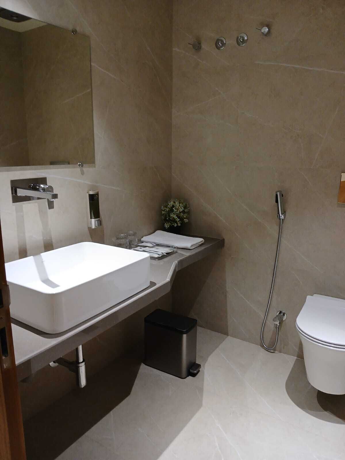 A modern bathroom with a white sink, mirror, and toilet.