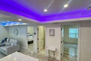 Une chambre moderne comprenant un lit, un canapé, une petite table et une porte donnant sur une autre pièce.