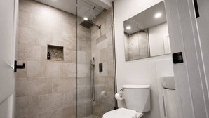 A modern bathroom with a glass-enclosed shower, a toilet, and a mirror above the sink. - Wavecrest Retreat (Near Strip & Beach) (Daytona Beach)