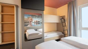 A hotel room with a bunk bed, a wardrobe, a painting, and a window with curtains.