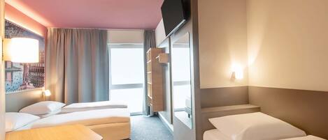 A hotel room with a bed, a desk, a chair, a TV, and a window.