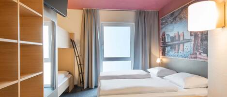 A hotel room with a bunk bed, a desk, a window with curtains, a wall-mounted TV, and a painting.
