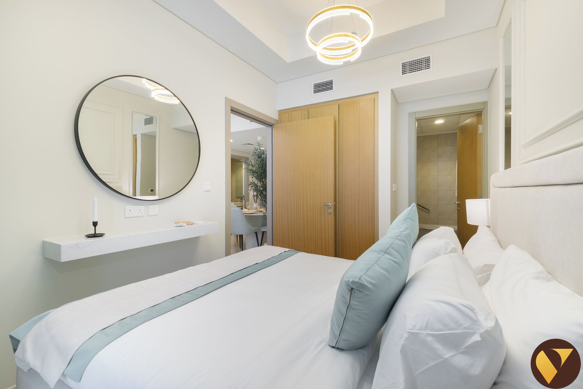 Une chambre à coucher moderne avec un grand lit, un miroir rond, une table de chevet et une armoire.