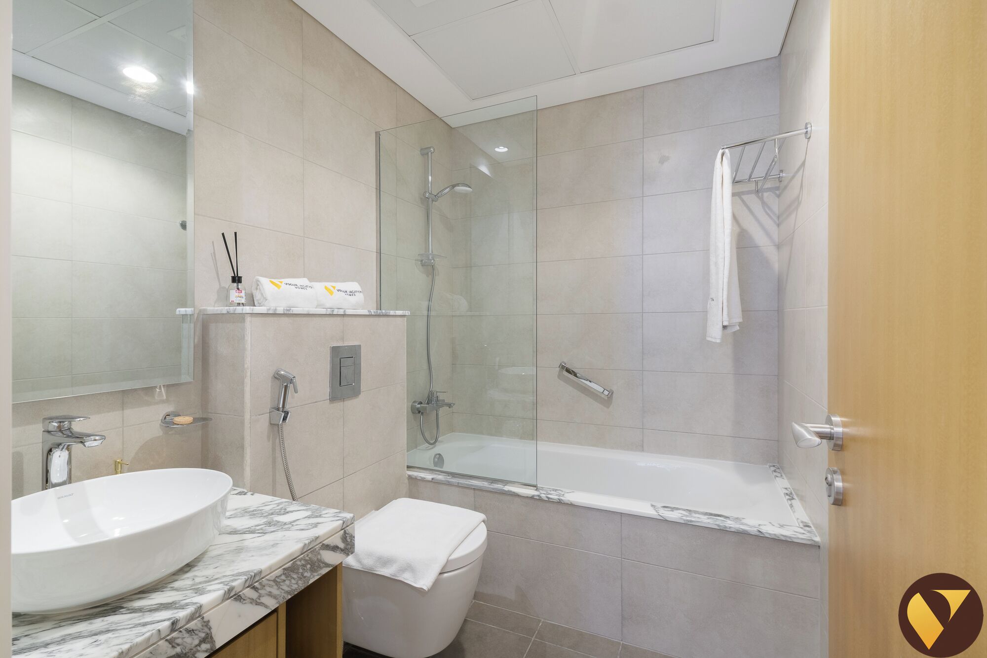 Une salle de bain moderne avec un lavabo en marbre, une douche à parois de verre et une baignoire.