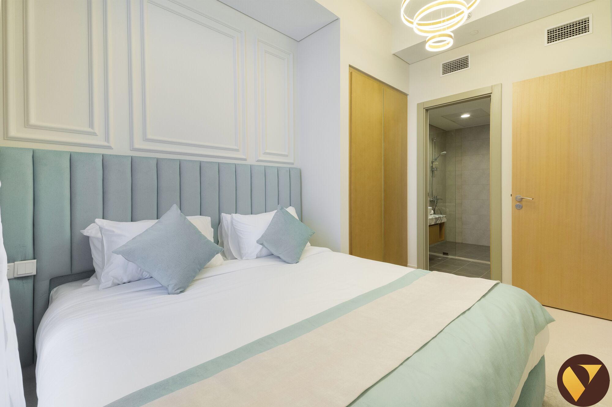 Een hotelkamer met een bed, een houten garderobe en een douchehoek.