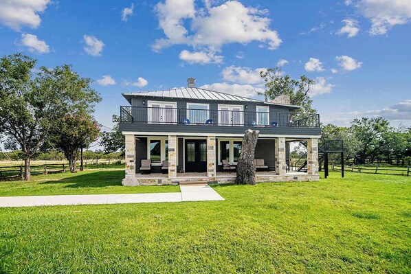 A two-story house with a covered porch and a stone foundation.