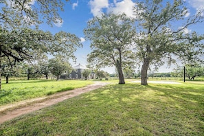 A grassy area with a dirt path leading to a building with a dark roof.