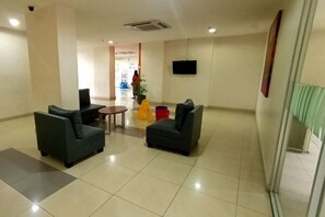 Eine Hotelhalle mit zwei Sofas, einem kleinen Tisch und einem an der Wand befestigten Fernseher.
