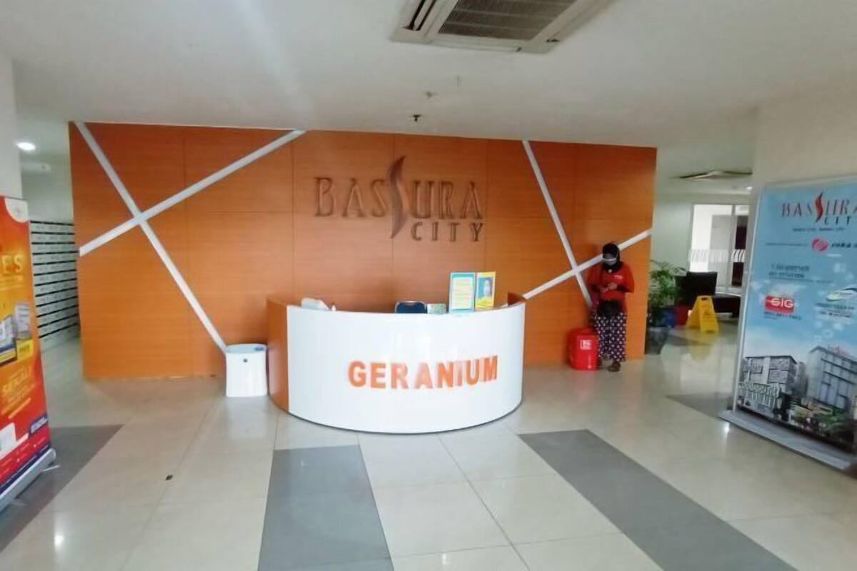 A reception desk with the sign "BASURA CITY" and "GERANIUM" written on it.