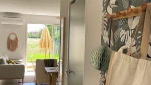 Ein Zimmer mit einer Couch, einem Esstisch, einem Hängekorbstuhl und Blick ins Freie.