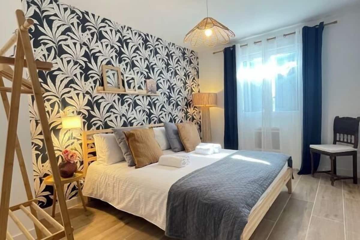 A bedroom with a bed, bedside table, lamp, and a window with curtains.