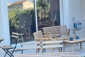 Une terrasse dotée de mobilier en bois, comprenant un canapé et des fauteuils, ainsi qu’une table avec des tasses et un livre.