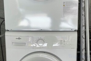 Vue de face d’un lave-linge, avec son panneau de commande, une étiquette d’avertissement de sécurité et sa porte.