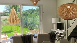 Ein modernes Wohnzimmer mit einer Couch, einem Fernseher und einem Essbereich mit Tisch und Stühlen.