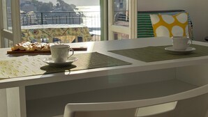 Un coin repas avec une table dressée pour deux personnes, une tasse et une soucoupe, et une assiette de nourriture.