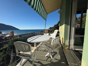 Un balcone con un tavolo rotondo e due sedie, con vista sulla costa.