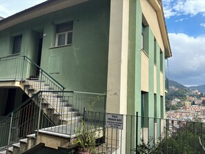 Un edificio con facciata verde, una scala con ringhiere in metallo e un segnale che indica un accesso privato.
