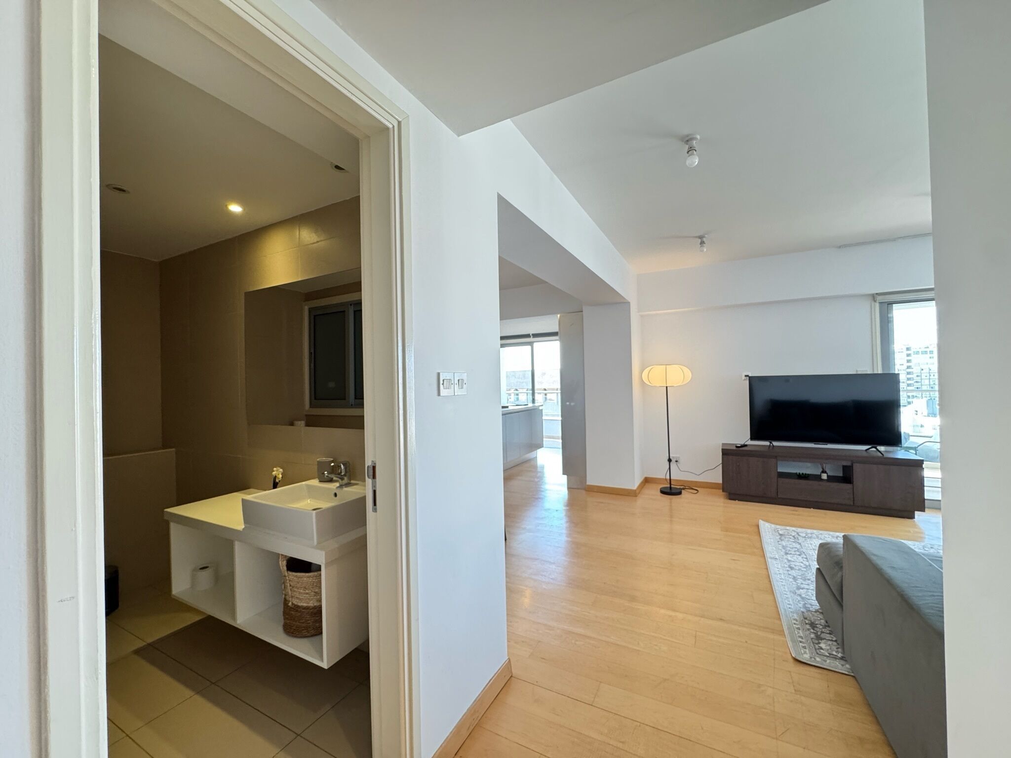 Una sala de estar moderna con un televisor de pantalla plana, un sofá y una lámpara de pie.