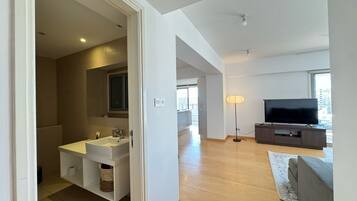 Una sala de estar moderna con un televisor de pantalla plana, un sofá y una lámpara de pie.