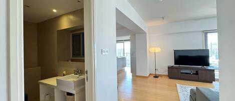 A modern living room with a flat-screen TV, a sofa, and a floor lamp.