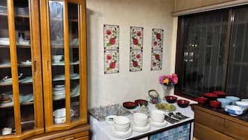 A kitchen with a wooden cabinet, a table with dishes, and a window with blinds.