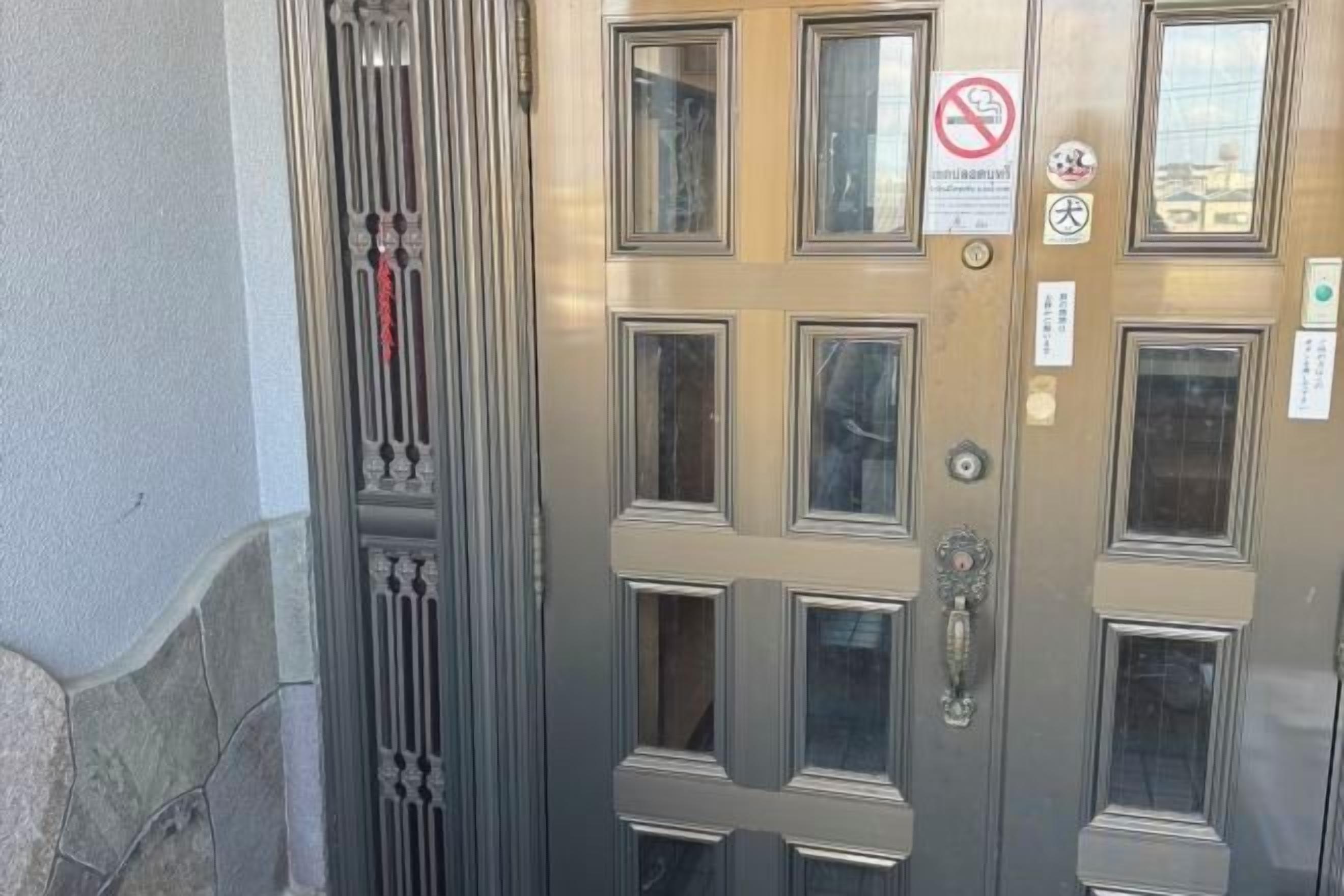 A metallic elevator door with multiple windows and a no-smoking sign.
