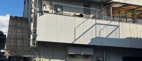A multi-story building with a closed garage door, external electrical boxes, and a visible balcony.