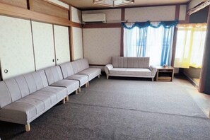 A room with a sofa, a small table, and a window with curtains. - Mito Houses 19-23 Pax - Breakfast Options (Higashiosaka)