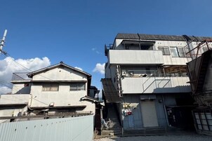 Un edificio de varios pisos con techo plano, una escalera visible y una entrada protegida por una reja.