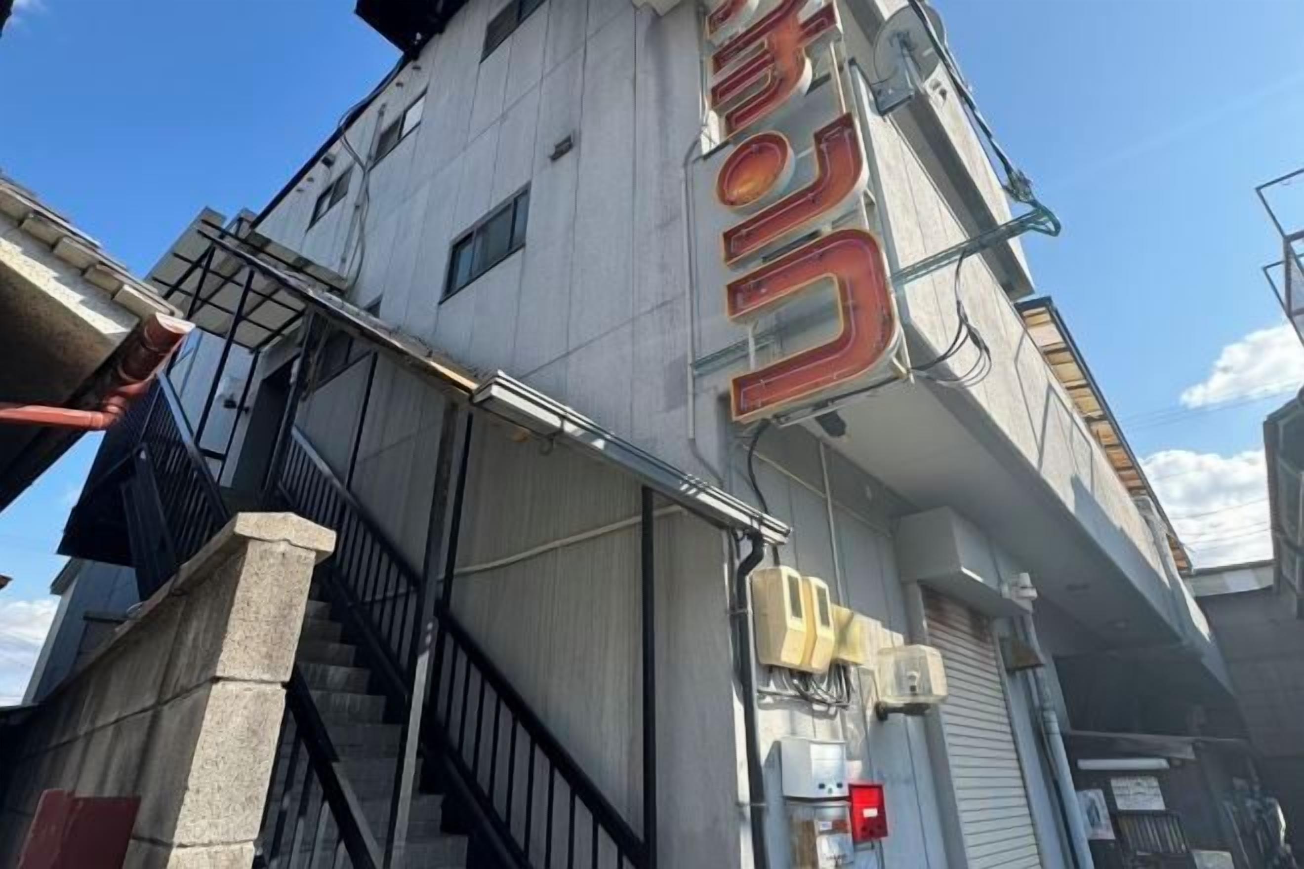A multi-story building with a prominent sign, a staircase, and a visible air conditioning unit.