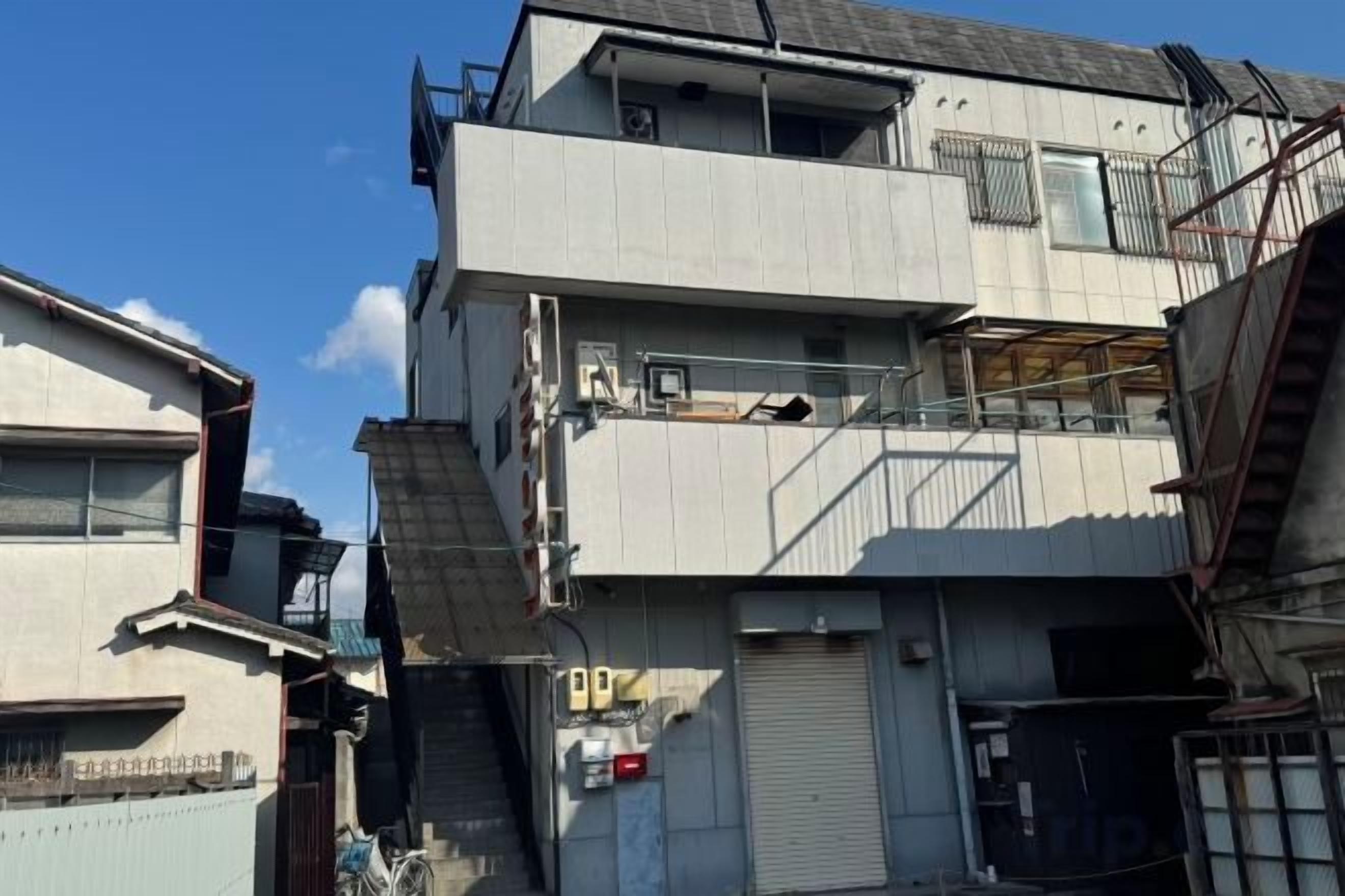Un edificio de varios pisos con techo plano, una escalera visible y un portón de garaje cerrado.