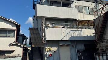 Un edificio de varios pisos con techo plano, una escalera visible y un portón de garaje cerrado.