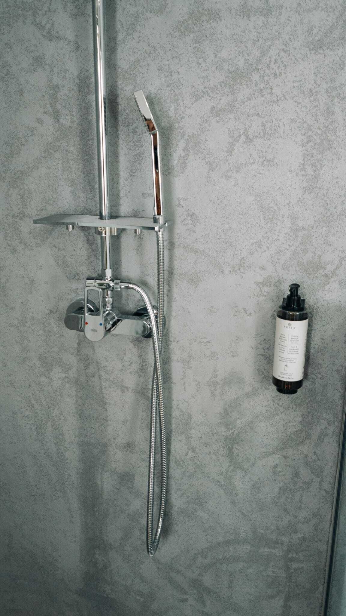 A shower with a handheld showerhead and a wall-mounted faucet.