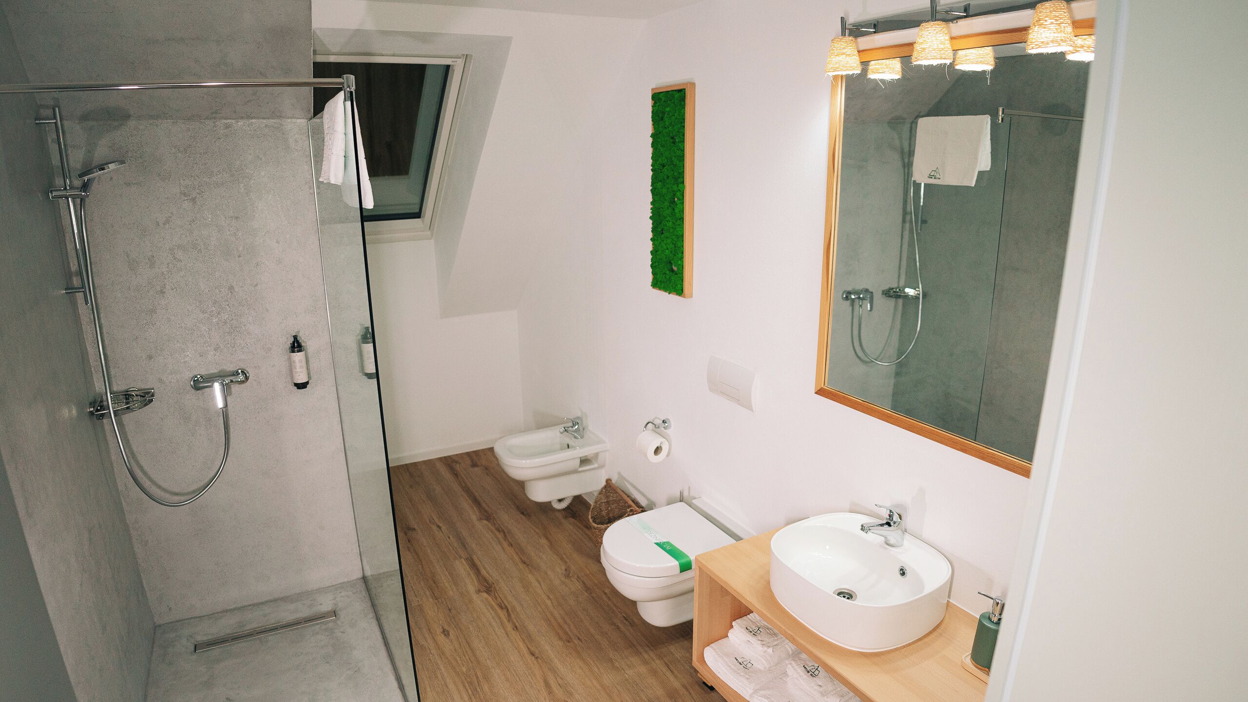 Un baño moderno con ducha acristalada, inodoro y lavabo con espejo.