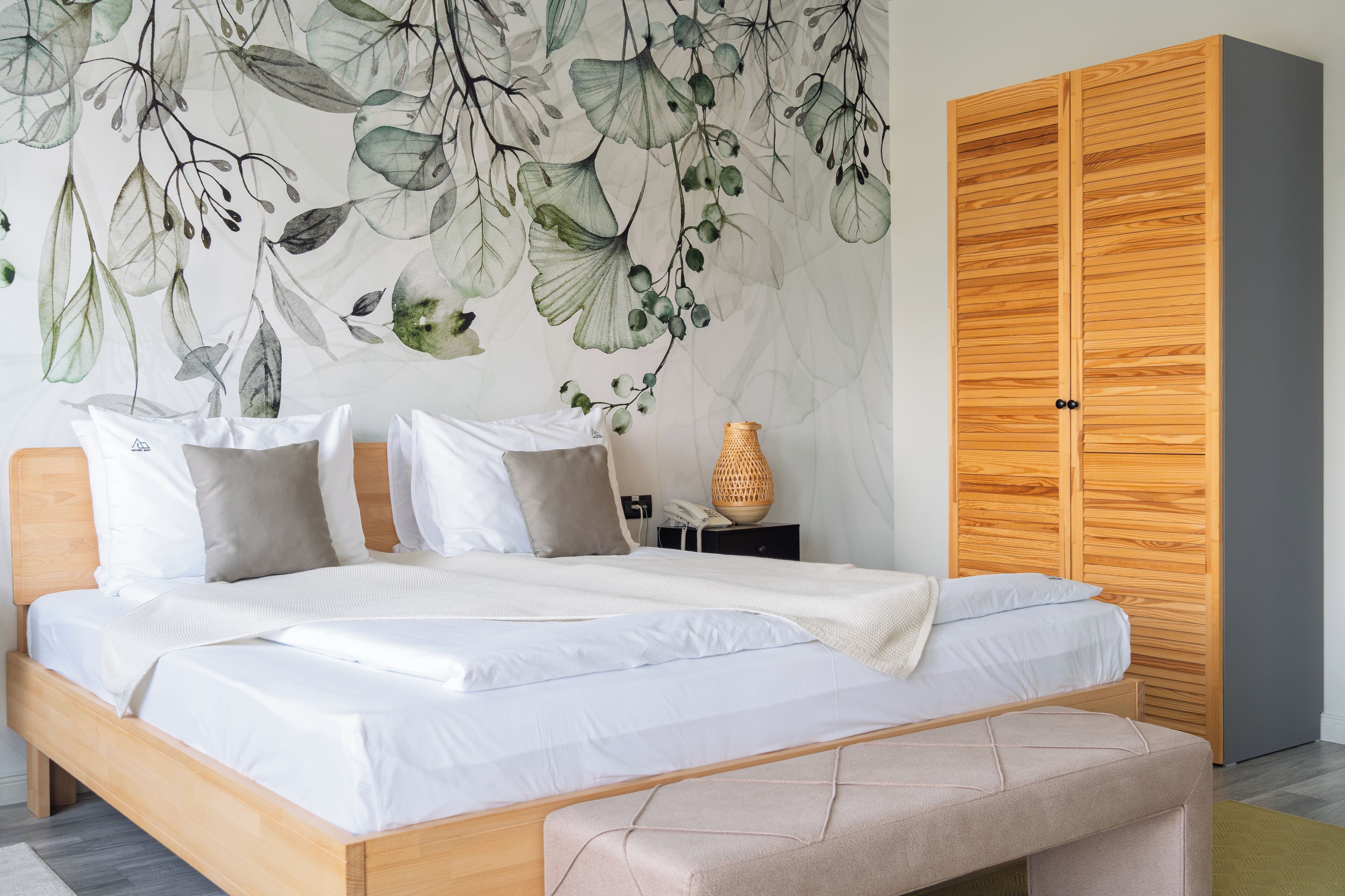Un dormitorio con cama, armario de madera, mural en la pared y mesita de noche con lámpara.