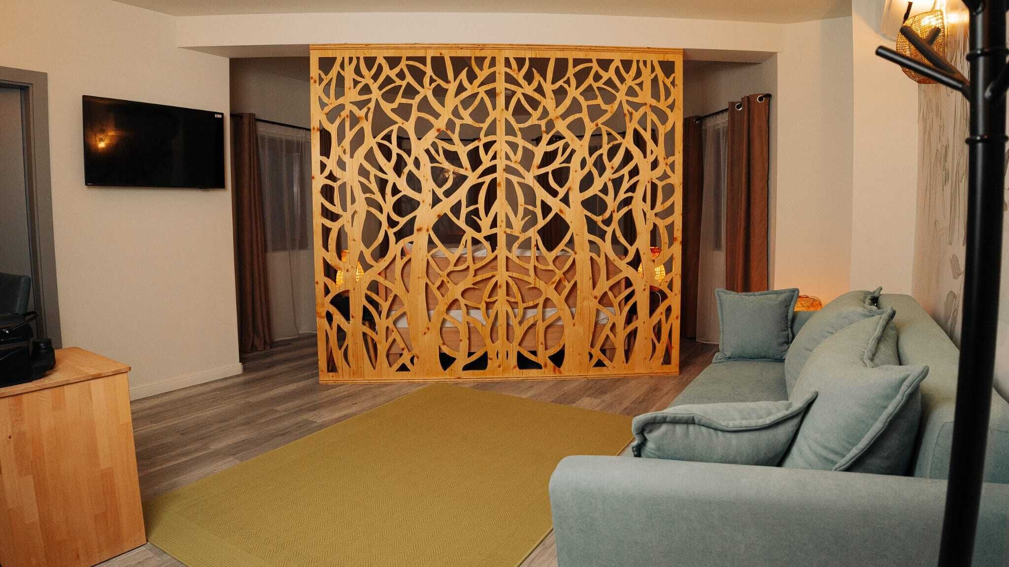 Una sala de estar con un sofá gris, un mueble de televisión de madera, un panel decorativo de madera y una alfombra amarilla.