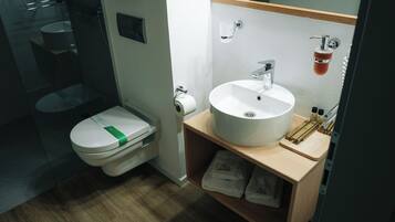 A compact bathroom with a toilet, sink, and storage shelf.