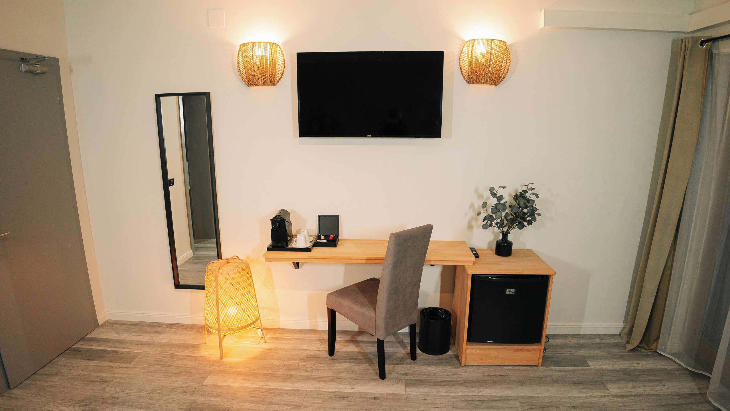 Una habitación moderna con un escritorio de madera, una silla, un televisor y una planta pequeña.