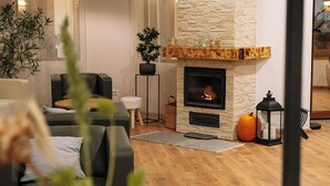 A cozy living room with a fireplace, a sofa, a coffee table, and a potted plant. - Nature Nest (Bran)