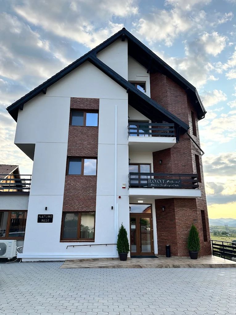A modern multi-story building with a flat roof, large windows, and a balcony.