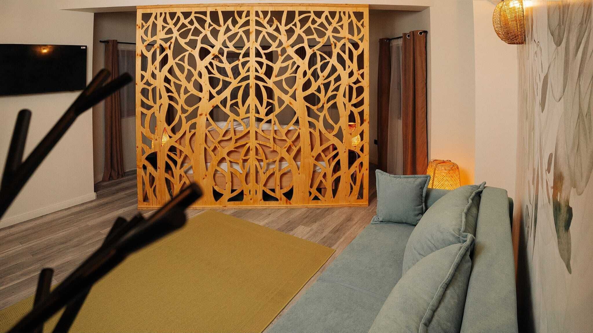 A modern living room with a wooden decorative partition, a sofa with cushions, and a yellow rug.