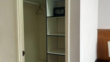A walk-in closet with a hanging rack and a microwave on the shelves.