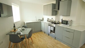 A compact kitchen with grey cabinets, a microwave, a toaster, and a sink. - The Swell by Guestz (Rhosneigr)