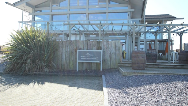 A building with a large glass facade, wooden exterior, and a sign indicating it is a 'COSTERCHER'. - The Swell by Guestz (Rhosneigr)