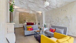 Een moderne woonkamer met een stenen muur, een bank, een gele fauteuil en een klein tafeltje met een bloevas.
