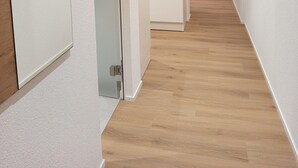 A hallway with wooden flooring, white walls, and artwork depicting animals. - Gästehaus Rossfall 424 - Self-Check-in (Urnaesch)