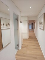 Un pasillo con suelo de madera, paredes blancas y obras de arte que representan animales.