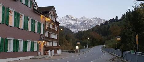 A street with buildings on one side and a mountain range in the background.