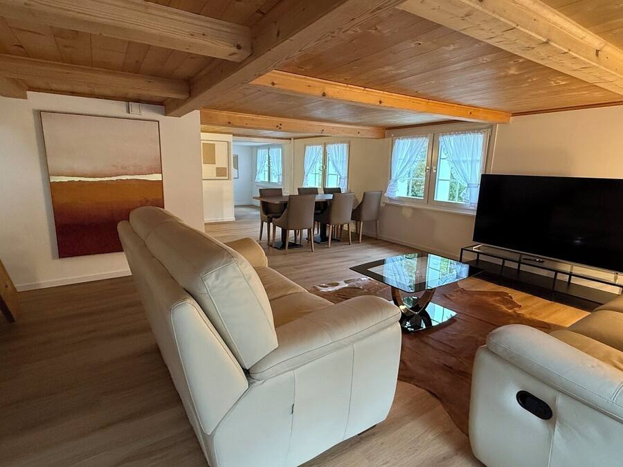 Amplia sala de estar con techo de madera, televisor de pantalla plana grande y comedor al fondo.
